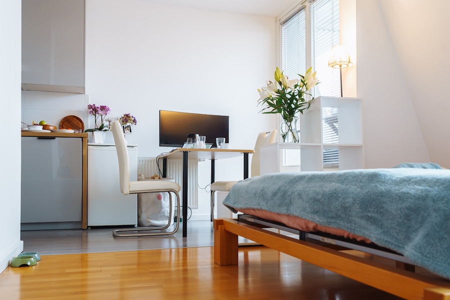 Pomieszczenie z łóżkiem otwarte na kuchnię z jadalnią
