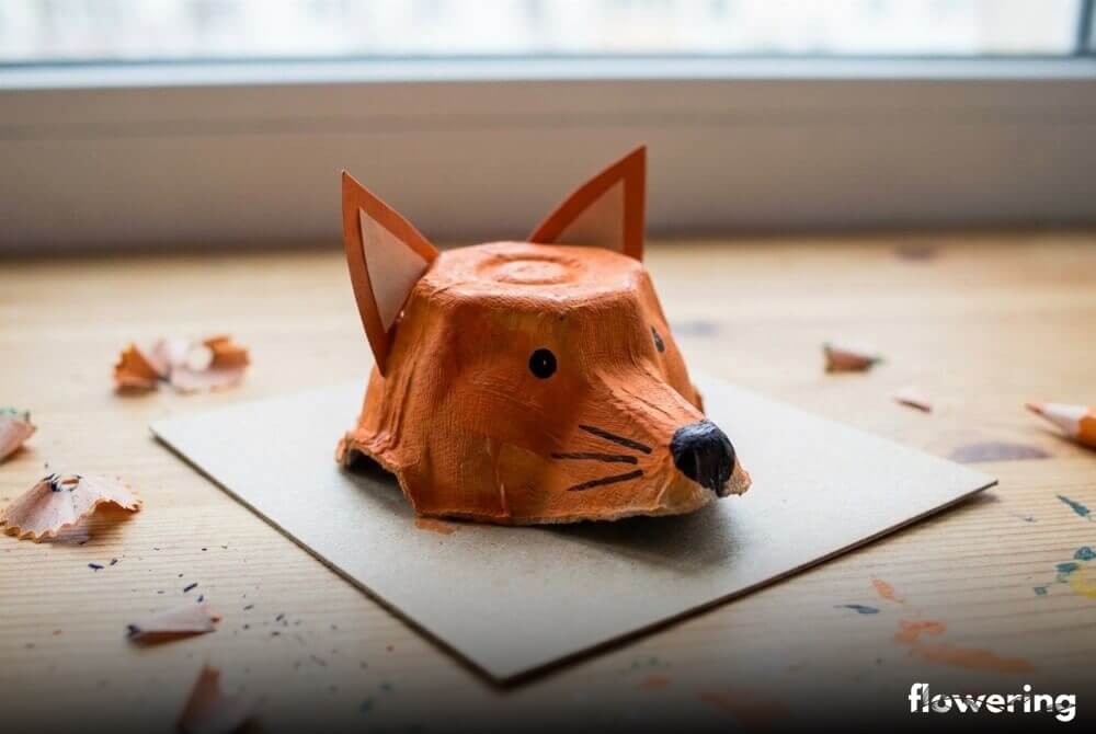 Lisi pyszczek z wytłaczanki po jajkach, pomalowany na pomarańczowo z papierowymi uszami i dorysowanym noskiem, jako obrazek 3D