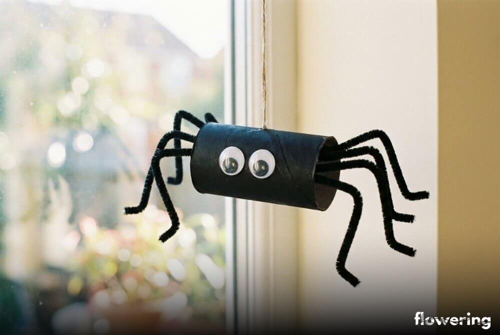 Pająk z czarnej rolki po papierze toaletowym z nogami z drucików kreatywnych i ruchomymi oczkami, wisząca dekoracja