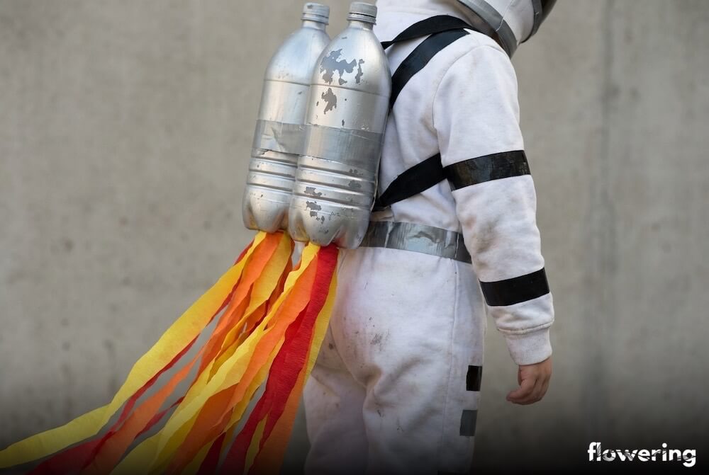 Strój astronauty z recyklingu z plecakiem odrzutowym z dwóch srebrnych butelek PET i „płomieniami” z bibuły, ujęcie z bliska