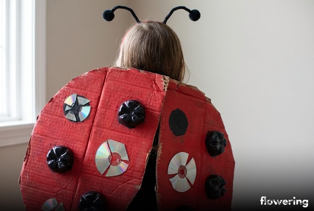 Strój biedronki z czerwoną peleryną i czarnymi kropkami z recyklingu oraz czułkami na opasce, ujęcie z bliska