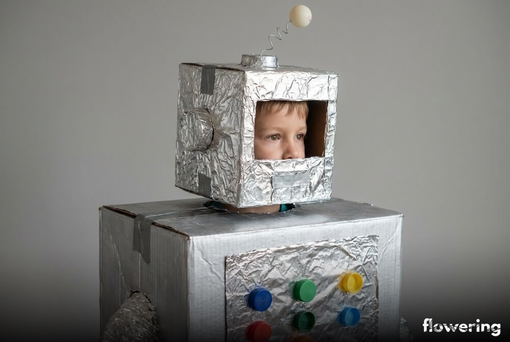 Dziecięcy strój robota z kartonów oklejonych folią aluminiową, z nakrętkami jako przyciskami i anteną na hełmie, ujęcie z bliska