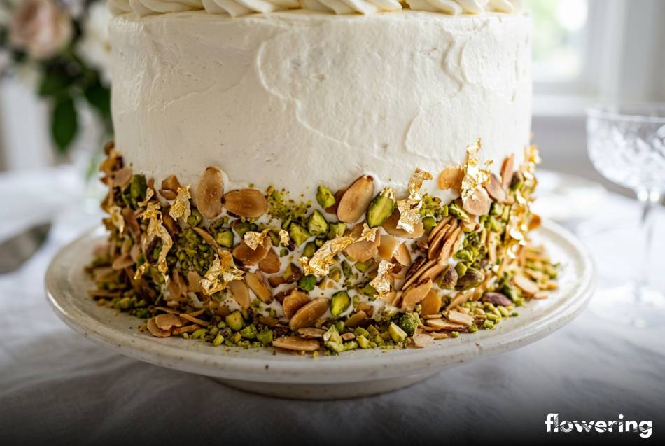 Dolna krawędź białego tortu z migdałami pistacjami i złotem