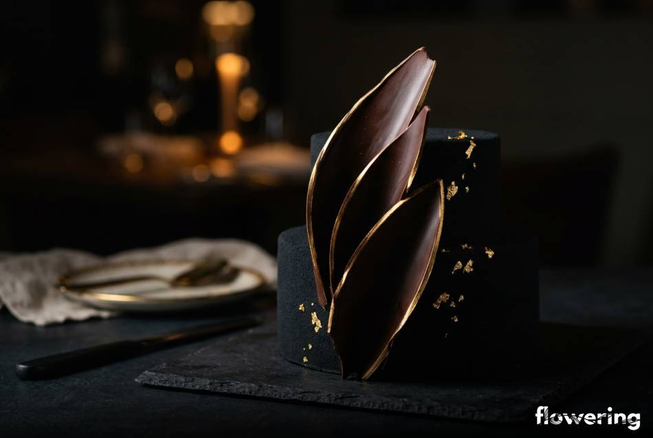 Czarny tort z jadalnym zamszem i złotymi żaglami czekoladowymi