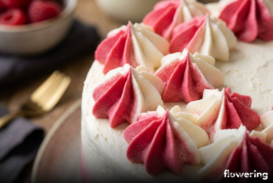 Biało-różowe rozety z kremu mascarpone i malin na torcie