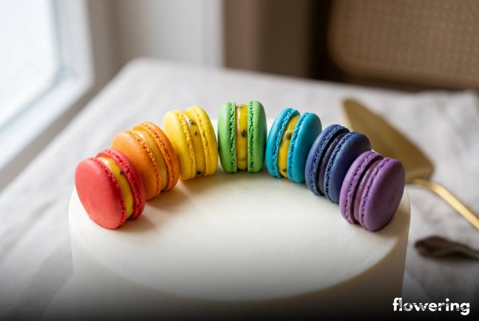 Tęczowe makaroniki francuskie ułożone w geometryczny półksiężyc na torcie
